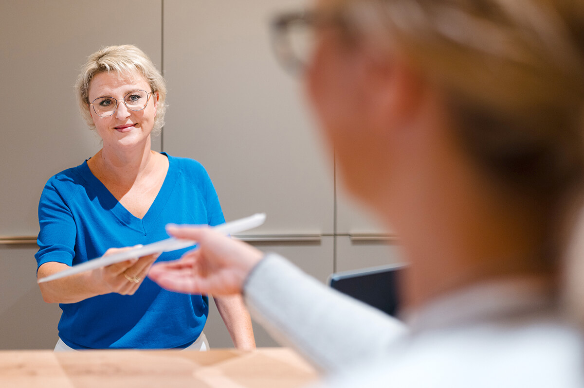 Arzthelferin übergibt Dokumente